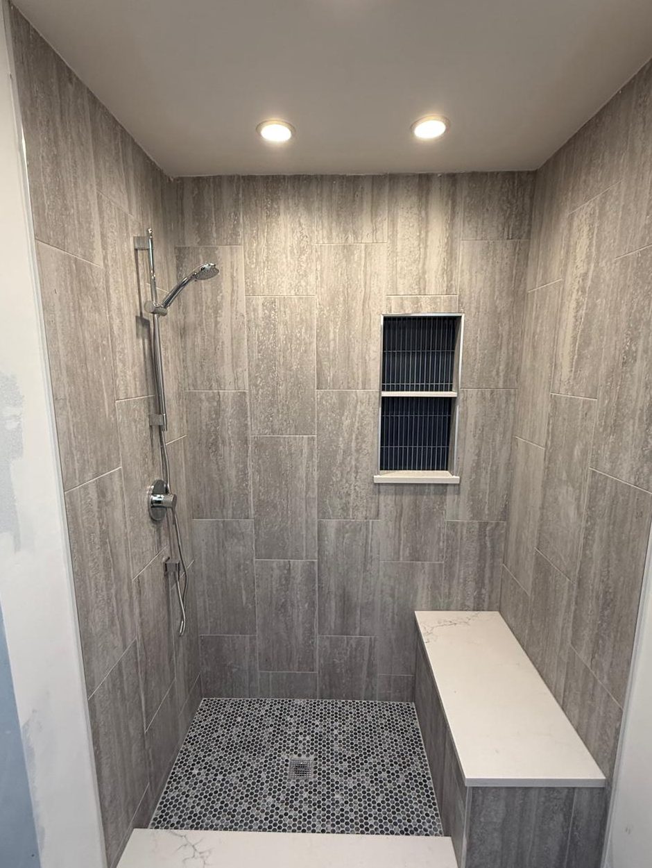 Tiled walk-in shower with a built-in bench, storage niche and penny tile floor